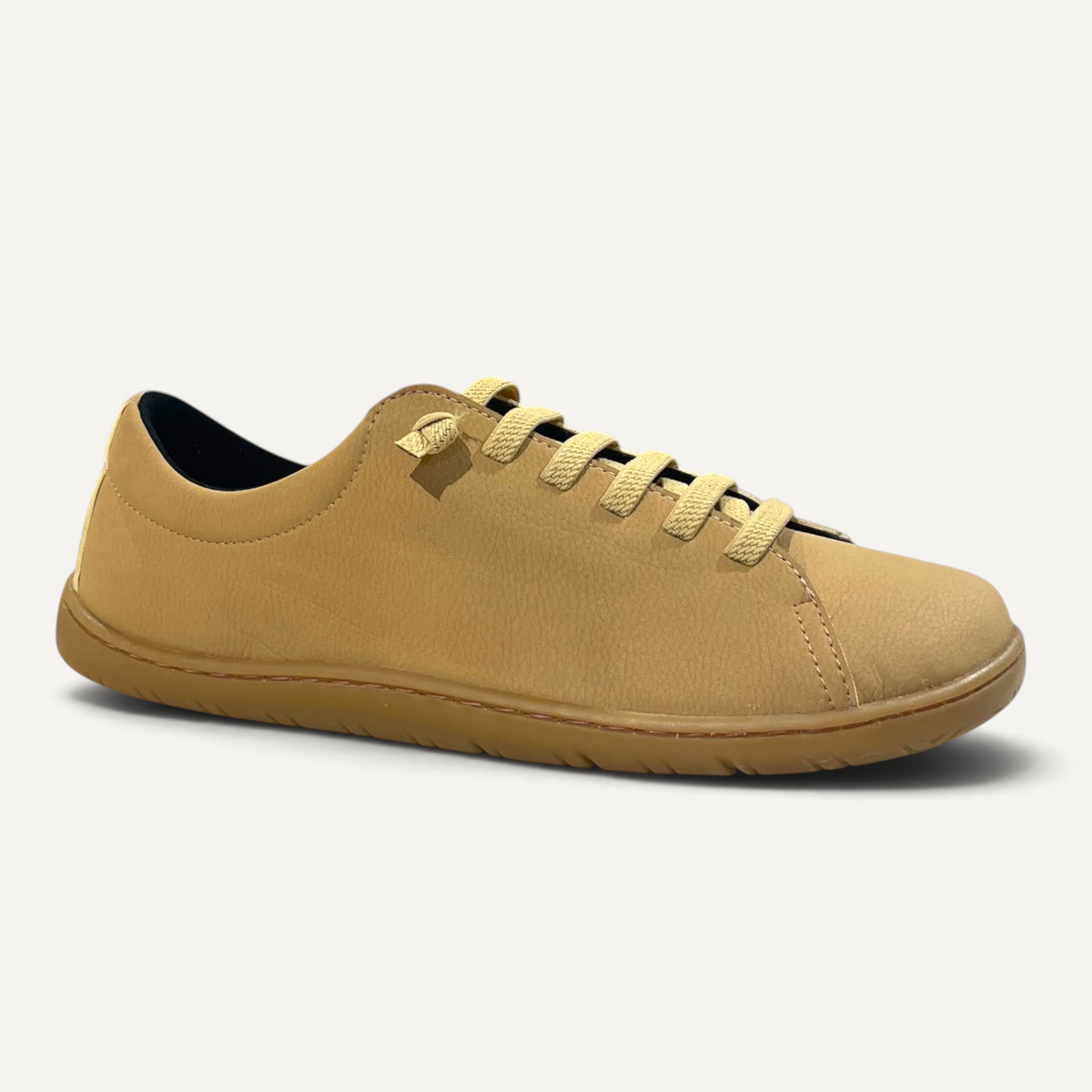 Zapatos barefoot zoireo Coqueflex Emi en color mostaza con diseño minimalista y suela plana en una tienda.