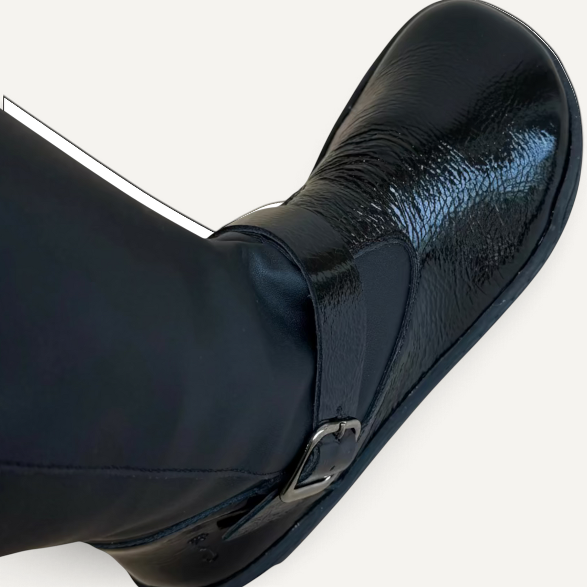 Bota barefoot Flexinens de caña alta en color negro con acabado brillante, forro de merinilla y hebilla de zoireo