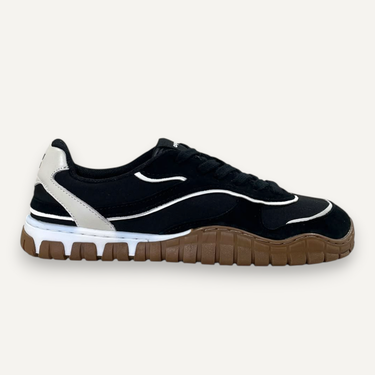 Zapatilla Coqueflex Kian de zoireo en color negro con detalles blancos y suela de goma marrón en una tienda